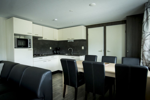 Cocina y comedor modernos en la Dune Lodge del Holiday Park Duinhoeve en los Países Bajos con decoración elegante.