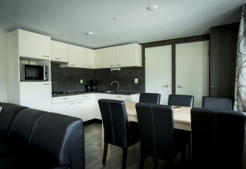 Moderne køkken og spisestue i Dune Lodge på Holiday Park Duinhoeve i Holland med sort-hvide møbler.