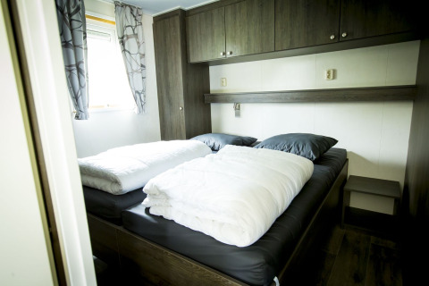 Schlafzimmer in der Dune Lodge im Holiday Park Duinhoeve, Niederlande, mit Doppelbett und modernen Möbeln.