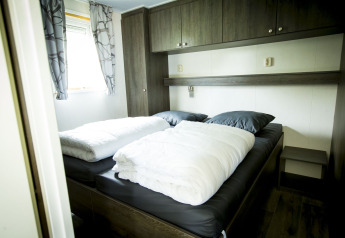 Schlafzimmer in der Dune Lodge im Holiday Park Duinhoeve, Niederlande, mit Doppelbett und modernen Möbeln.