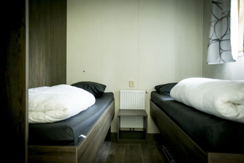 Ein einfaches Doppelzimmer mit zwei Einzelbetten in der Dune Lodge im Holiday Park Duinhoeve, Niederlande.