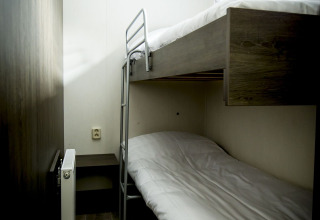 Kleine kamer met stapelbed en modern interieur in Dune Lodge bij Holiday Park Duinhoeve, Nederland.