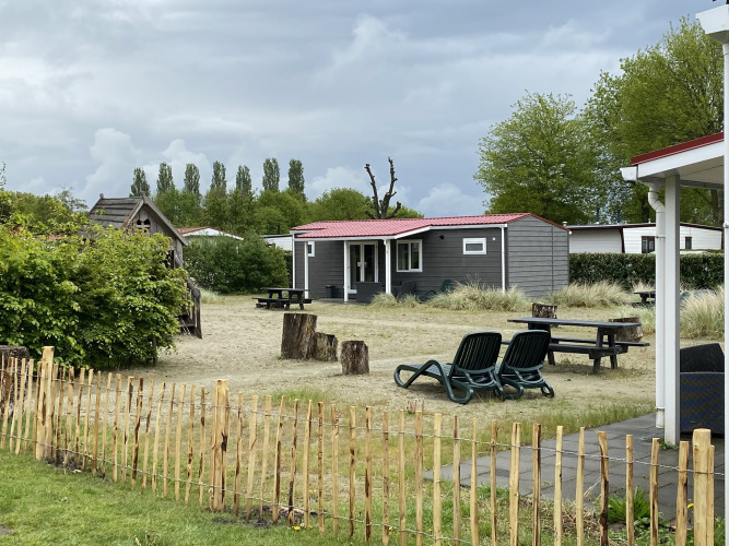 Vista exterior de la Dune Lodge en Holiday Park Duinhoeve, Países Bajos, con jardín y zonas de descanso.