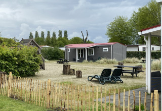 Buitenaanzicht van de Dune Lodge op Vakantiepark Duinhoeve, Nederland, met tuin en zitplekken.