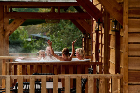 Family enjoying a hot tub at Heydehuis lodge in Sandberghe, Netherlands, surrounded by wooden beams.