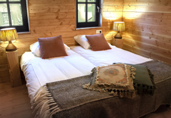Habitación acogedora en Heydehuis glamping con cama doble, paredes de madera y cálidas lámparas de noche.