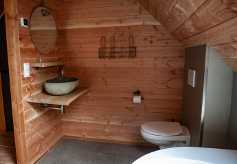 Moderne houten badkamer in Heydehuis lodge in Sandberghe, Nederland, met stenen waskom en hangtoilet.