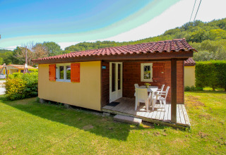 Chalet luminoso con terraza y muebles de jardín sobre césped verde en La Draille, Francia, con cielo soleado.