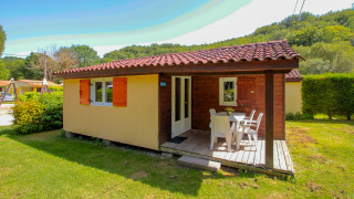 Chalet luminoso con terraza y muebles de jardín sobre césped verde en La Draille, Francia, con cielo soleado.