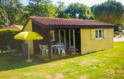 Chalet Borrèze en La Draille, Francia, con porche, muebles de jardín y una sombrilla amarilla sobre césped.