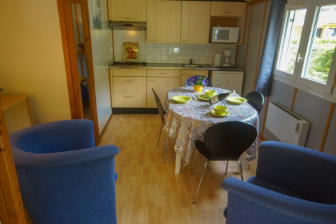 Cocina y comedor acogedores con mesa puesta, cuatro sillas y sillones azules en Chalet Borrèze, La Draille.