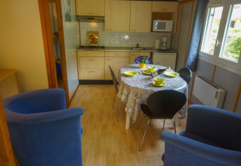 Cocina y comedor acogedores con mesa puesta, cuatro sillas y sillones azules en Chalet Borrèze, La Draille.