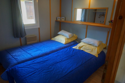 Dos camas individuales con edredones azules y almohadas amarillas en una habitación de Chalet Borrèze en La Draille, Francia.