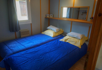 Dos camas individuales con edredones azules y almohadas amarillas en una habitación de Chalet Borrèze en La Draille, Francia.
