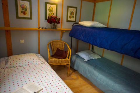 Habitación acogedora en Chalet Borrèze, La Draille, Francia con camas, silla de mimbre y cuadros en la pared.