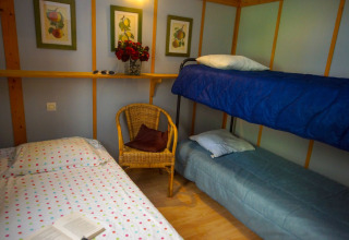 Habitación acogedora en Chalet Borrèze, La Draille, Francia con camas, silla de mimbre y cuadros en la pared.