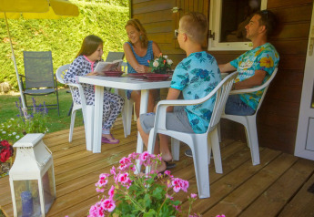 En familie sidder og hygger sig på terrassen ved Chalet Borrèze, La Draille i Frankrig, omgivet af blomster.