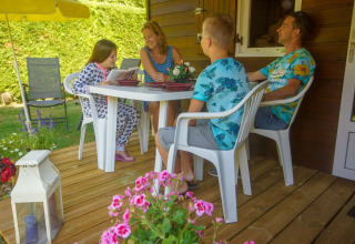En familie sidder og hygger sig på terrassen ved Chalet Borrèze, La Draille i Frankrig, omgivet af blomster.