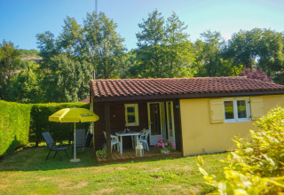 Hyggelig Chalet Borrèze-lodge ved La Draille i Frankrig, omgivet af haver og grønne træer under blå himmel.
