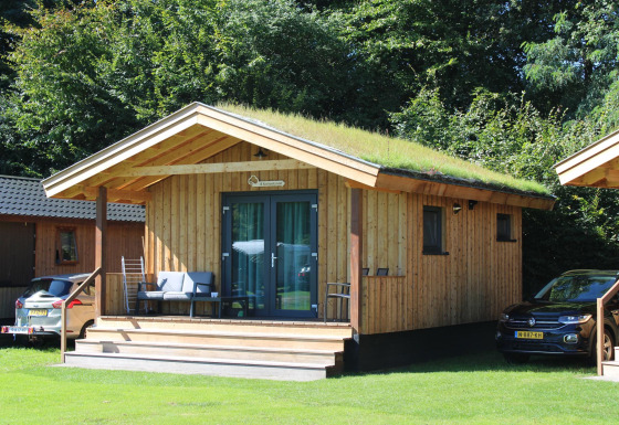 Petite maison en bois nommée Cuckoo's Nest avec toit végétalisé au Camping de Koeksebelt, Pays-Bas, voitures.