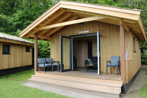 Tiny house Cuckoo's Nest au Camping de Koeksebelt aux Pays-Bas, terrasse en bois et fauteuils extérieurs.