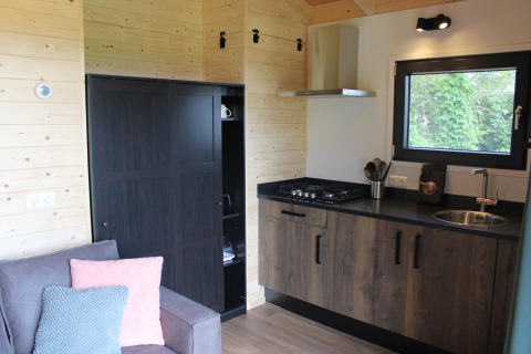 Cucina e soggiorno compatti nel tiny house Cuckoo's Nest a Camping de Koeksebelt, Paesi Bassi.