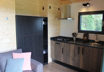 Køkkenområde i et tiny house ved Camping de Koeksebelt, Cuckoo's Nest, med trævægge og sofa.