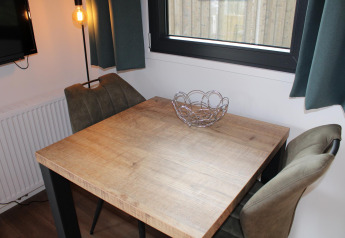 Eethoek met houten tafel, twee stoelen en metalen fruitschaal in Cuckoo's Nest, Camping de Koeksebelt.