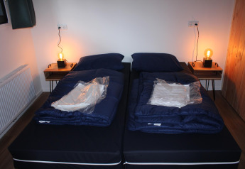 Deux lits simples dans la tiny house Cuckoo's Nest au Camping de Koeksebelt, Pays-Bas, avec tables de nuit.