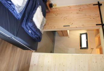Innenaufnahme des Tiny House Cuckoo's Nest auf Camping de Koeksebelt mit Bett und Holz-Schiebetür.