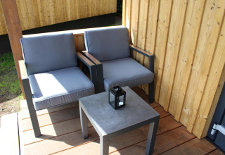 Dos sillones grises y una mesa con farol en la terraza de la tiny house Cuckoo's Nest en los Países Bajos.