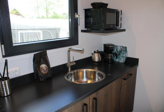 Moderne lille køkkenplads med vask, el-kedel, kaffemaskine og mikrobølgeovn i Cuckoo's Nest, Camping de Koeksebelt.
