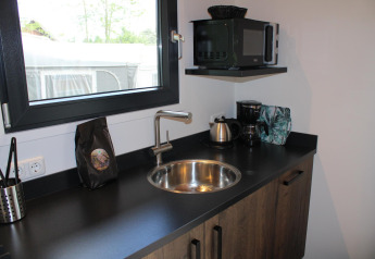 Compact kitchenette featuring a sink, kettle, coffee maker, and microwave in Cuckoo’s Nest, Camping de Koeksebelt.