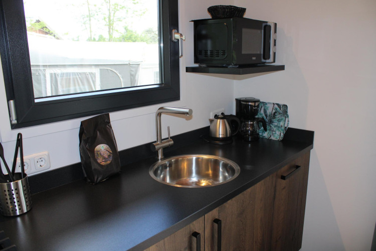 Compact kitchenette featuring a sink, kettle, coffee maker, and microwave in Cuckoo’s Nest, Camping de Koeksebelt.