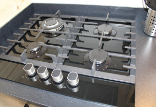 Cucina a gas moderna con quattro fuochi in una tiny house chiamata Cuckoo's Nest, Camping de Koeksebelt, Paesi Bassi.