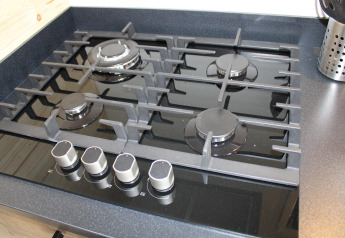 Cucina a gas moderna con quattro fuochi in una tiny house chiamata Cuckoo's Nest, Camping de Koeksebelt, Paesi Bassi.