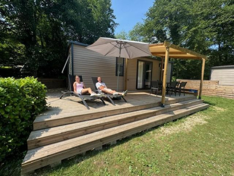 Two people relax on lounge chairs at Mobilhome Toulouse lodge at La Draille in France, surrounded by greenery.