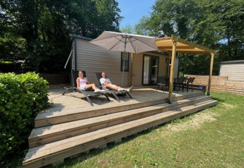 Two people relax on lounge chairs at Mobilhome Toulouse lodge at La Draille in France, surrounded by greenery.