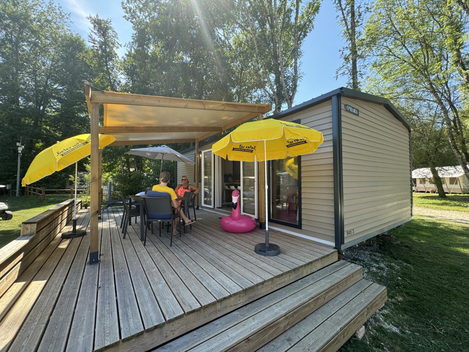 Buitenterras van Mobilhome Toulouse bij La Draille, Frankrijk, met parasols en ontspannende mensen.
