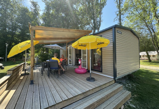 Outdoor deck of Mobilhome Toulouse at La Draille, France, with umbrellas and people relaxing on chairs.