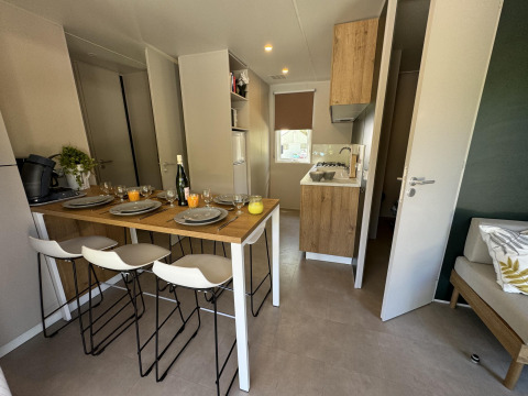 Cocina y comedor modernos en Mobilhome Toulouse de La Draille, Francia, con mesa puesta para cuatro personas.