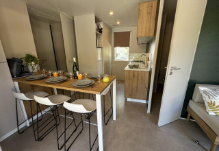 Cocina y comedor modernos en Mobilhome Toulouse de La Draille, Francia, con mesa puesta para cuatro personas.