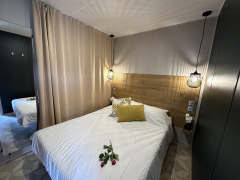 Acogedor dormitorio en Mobilhome Toulouse, La Draille, Francia, con cama doble y lámparas colgantes modernas.