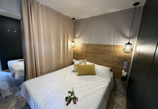 Cozy bedroom at Mobilhome Toulouse, La Draille, France, with a double bed, wooden headboard, and pendant lights.