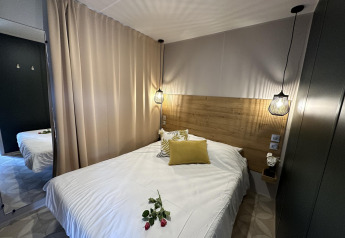 Hyggeligt soveværelse i Mobilhome Toulouse på La Draille, Frankrig, med dobbeltseng og moderne belysning.
