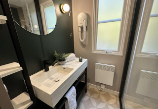 Baño moderno en Mobilhome Toulouse en La Draille, Francia, con lavabo, espejo y ventanas grandes.