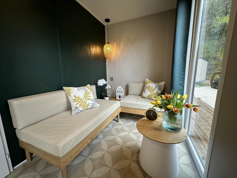 Moderne lounge in Mobilhome Toulouse bij La Draille, Frankrijk, met lichte banken en glazen deuren naar buiten.