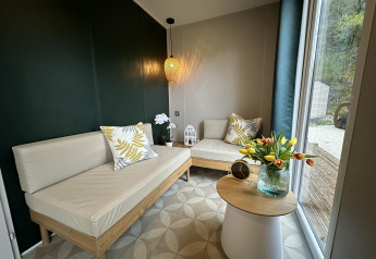 Salón moderno en Mobilhome Toulouse de La Draille, Francia, con sofás claros y gran ventanal al exterior.