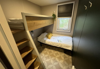 Dormitorio pequeño en Mobilhome Toulouse, La Draille, Francia, con litera, ventana y armario moderno.