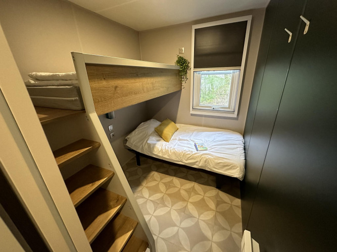 Petite chambre au Mobilhome Toulouse à La Draille, France, avec lit superposé et fenêtre lumineuse.